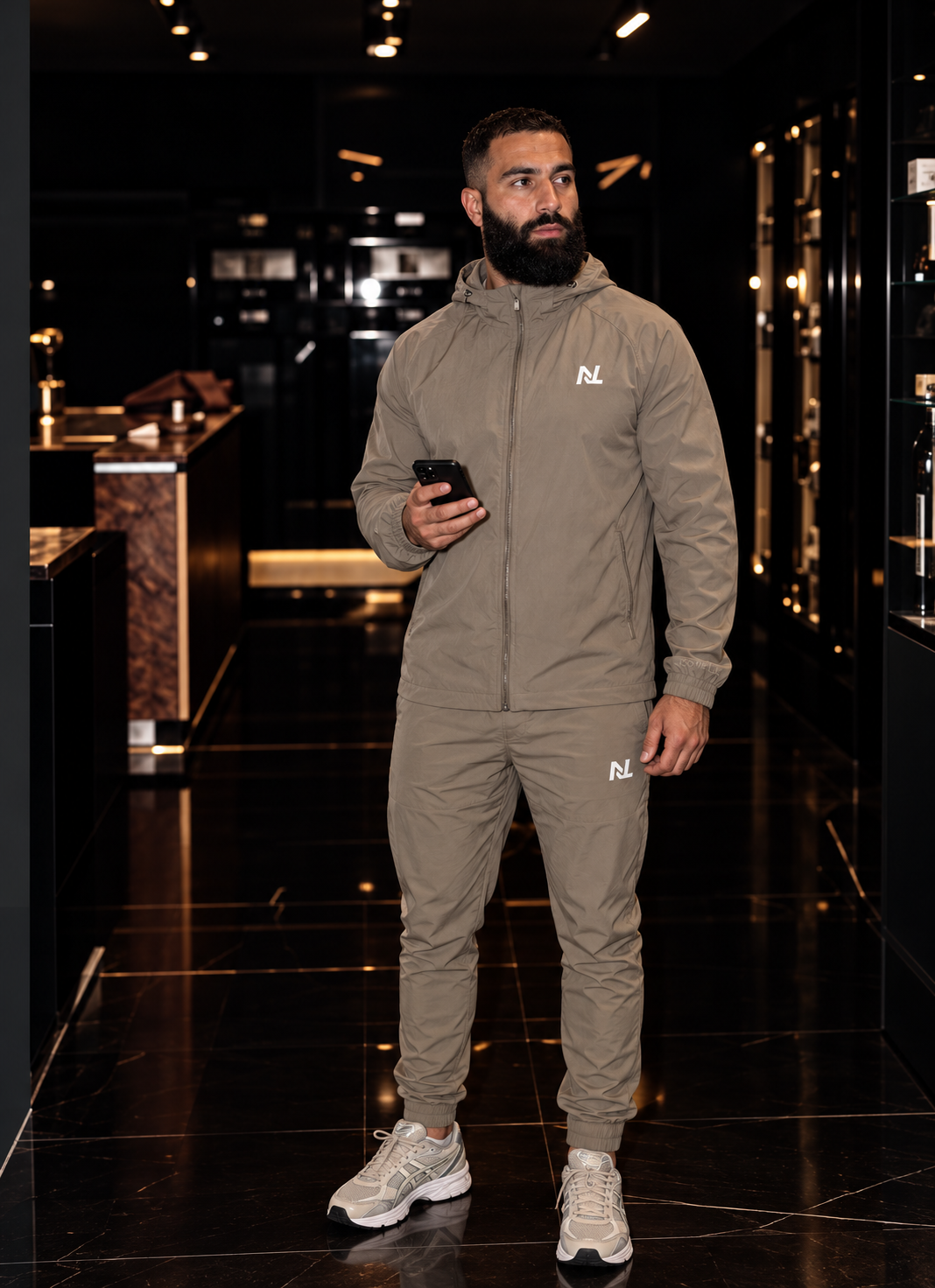 Model in een taupe Novélle-tracksuit in een showroom.